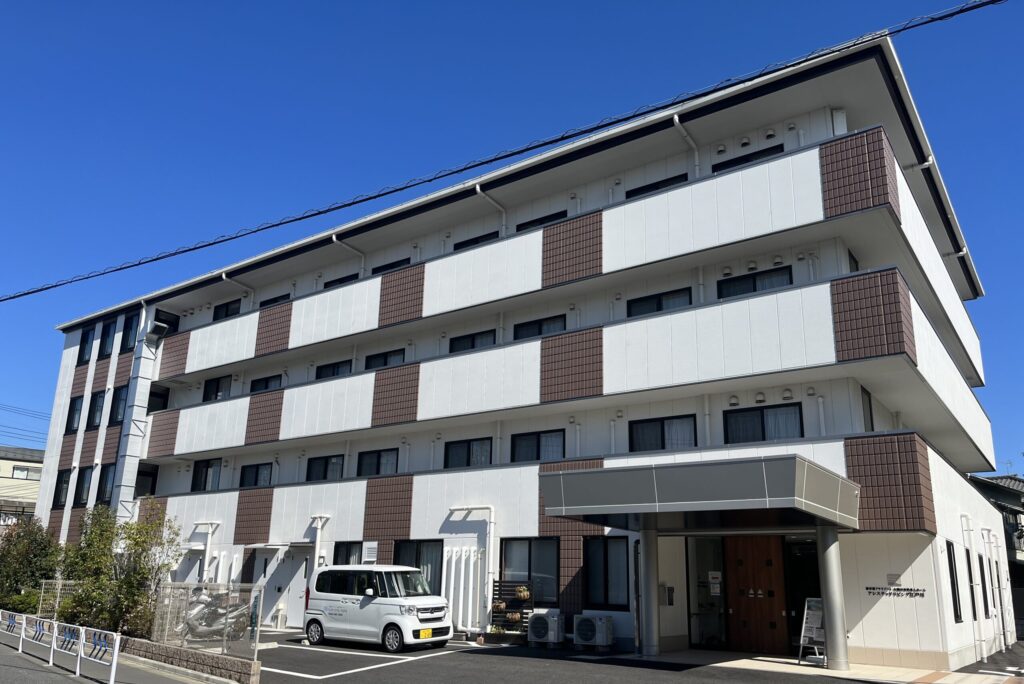 白とブラウンのツートンカラーの介護施設の建物外観。晴天で全体が鮮明に見える。
