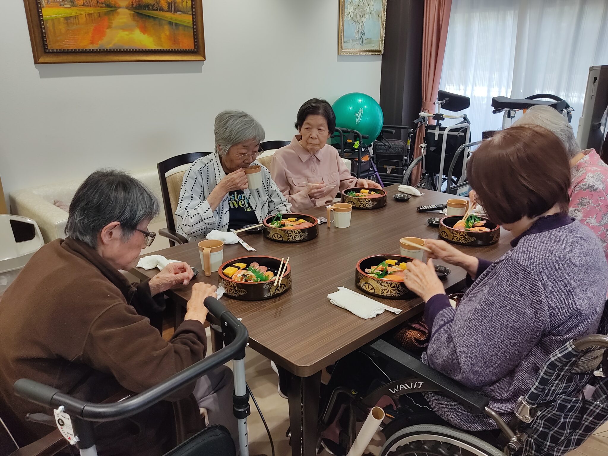 介護施設での食事風景。高齢者が一緒に食卓を囲み、楽しく食事をしている様子。