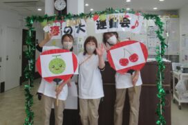 入居者と職員が食事イベントで飾られた空間で、手作り装飾品を持って笑顔で記念撮影している様子